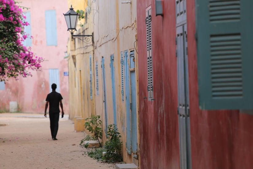 Silhouette of a lonely man walking in a narrow colored street of