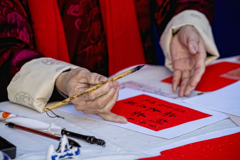 Hands of Chinese man, writing on a paper.