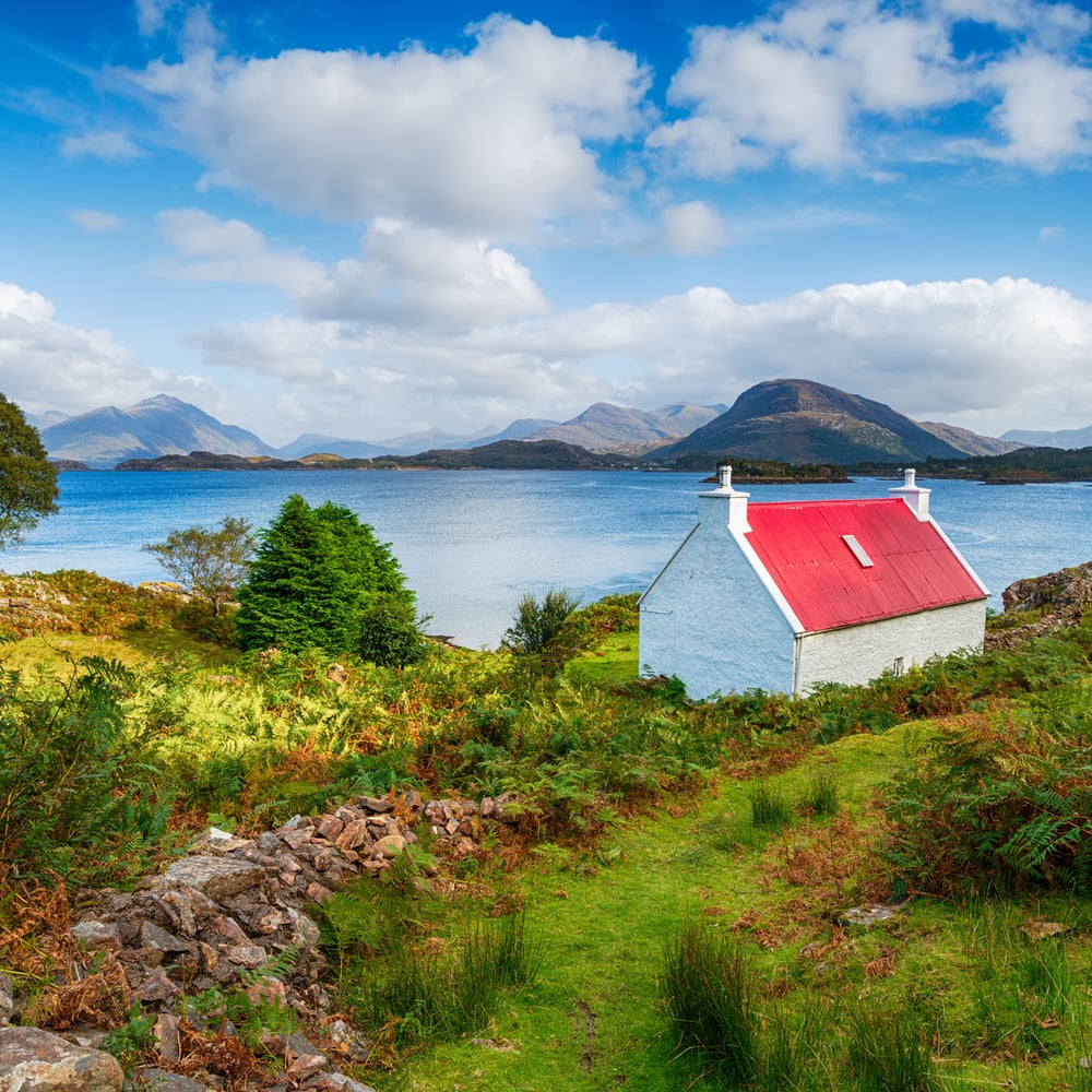 A pretty red roofed croft on the shores of Loch Shieldaig on the Applecross Peninsula in the Highlands of Scotland